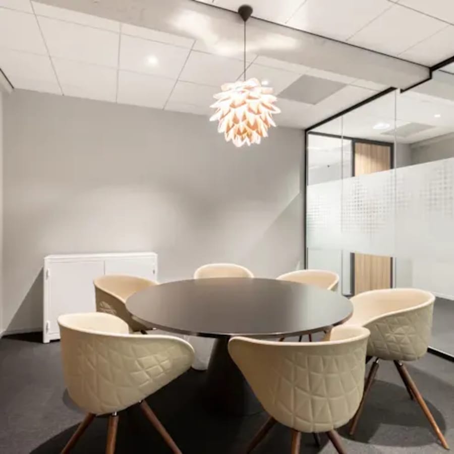 Stylish meeting room with modern chandelier and comfortable seating in a coworking space.