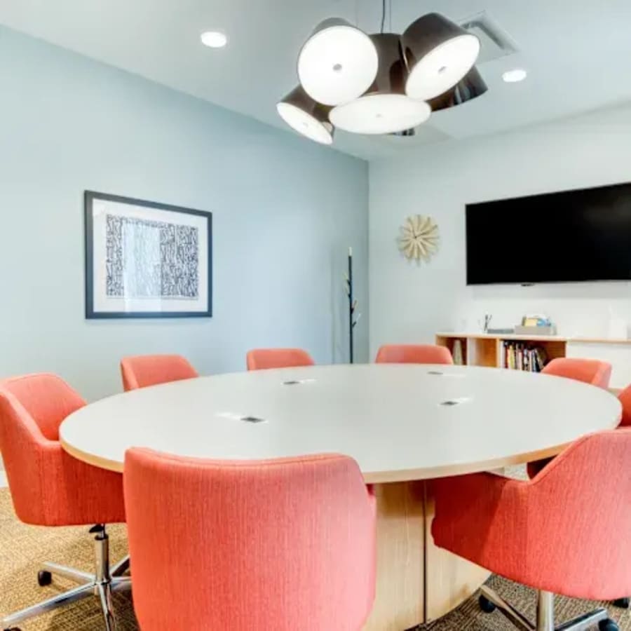 Bright meeting room with modern lighting, vibrant red chairs, and a large conference table.