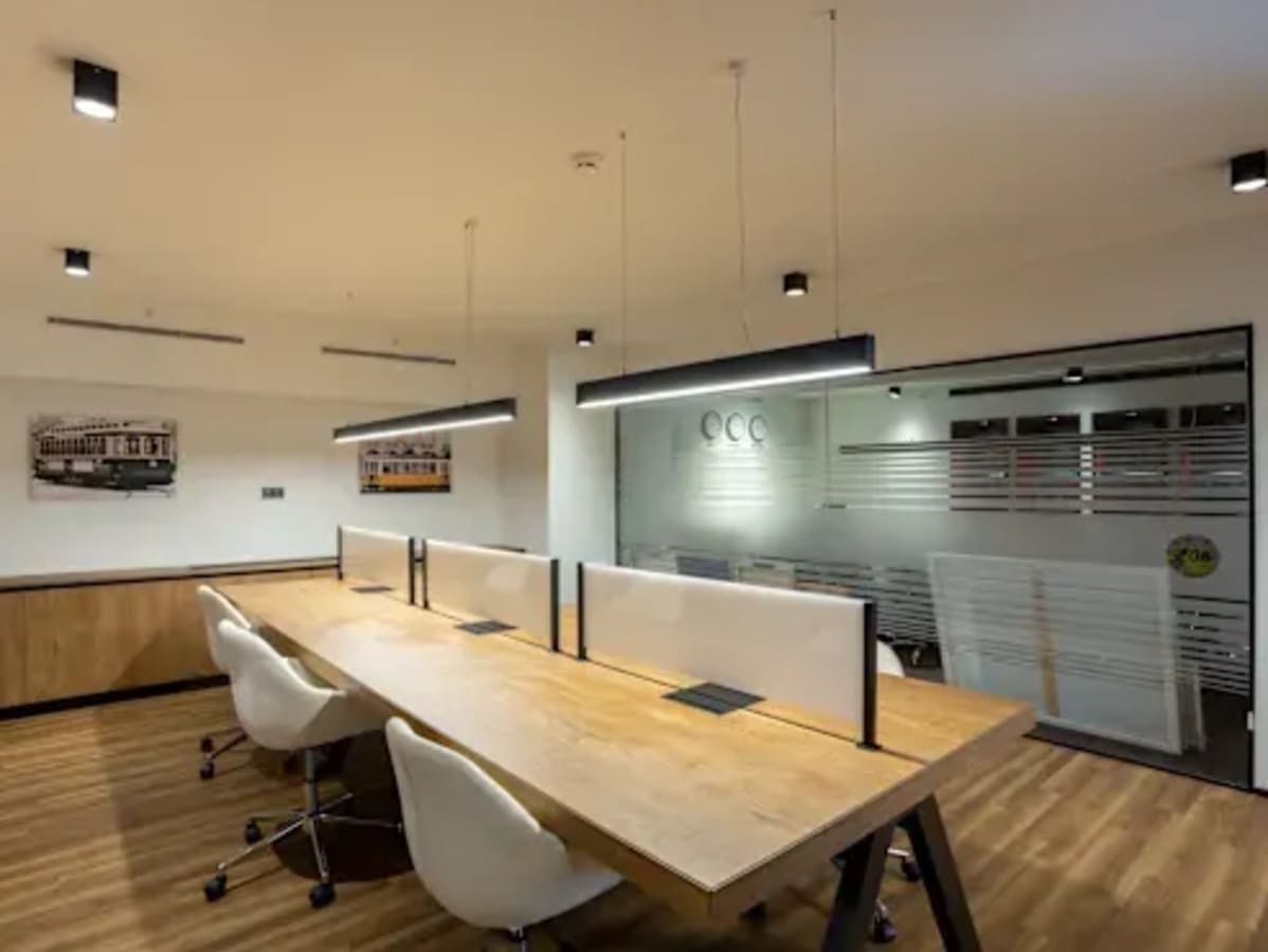 Modern coworking space with sleek wooden desks, stylish chairs, and ambient lighting on Kamarajar Road.