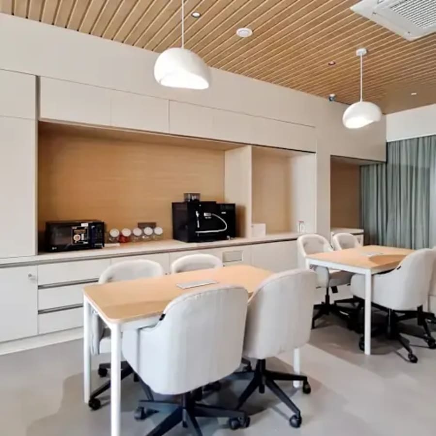 Modern coworking space with sleek furniture, ample lighting, and a functional kitchenette.