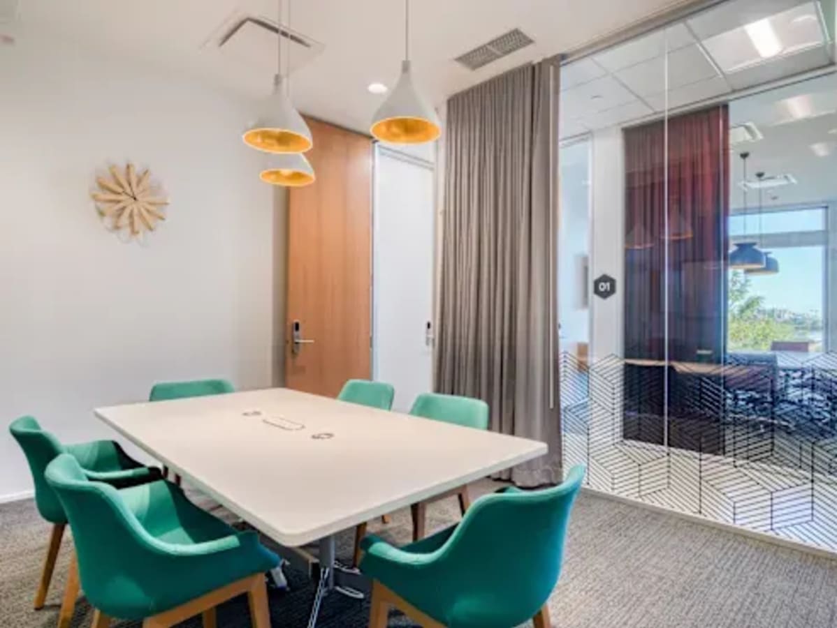 Sleek meeting room with modern decor, vibrant chairs, and ample natural light. Ideal for collaboration.