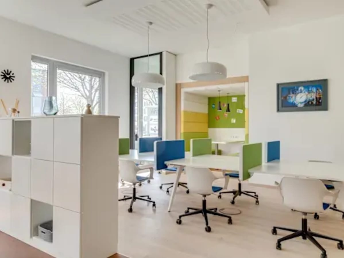 Bright coworking area with modern desks, colorful partitions, and ample natural light.