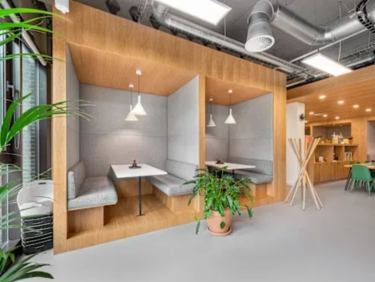 Modern coworking space with cozy booths, ample greenery, and stylish lighting on Mahatma Gandhi Road.