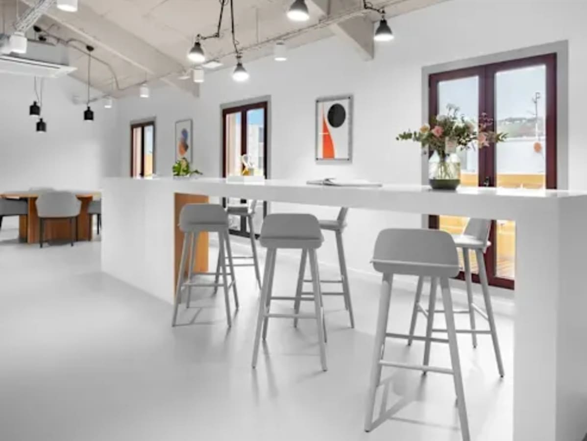 Modern coworking space with high ceilings, ample natural light, and sleek bar seating.