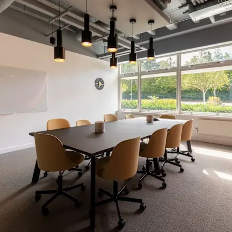 Bright meeting room with modern lighting, a large table, and ergonomic chairs. Ideal for collaboration.