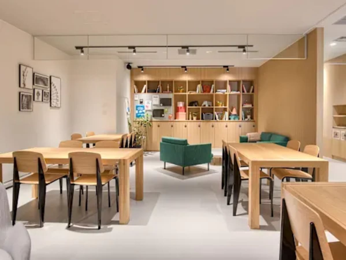 Modern coworking space with versatile seating, natural wood tables, and inviting lounge area.