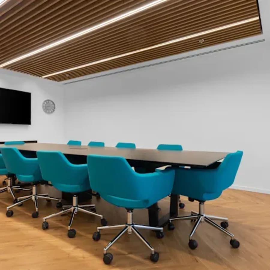 Sleek conference area with modern chairs, wooden ceiling, and ample natural light. Ideal for meetings.