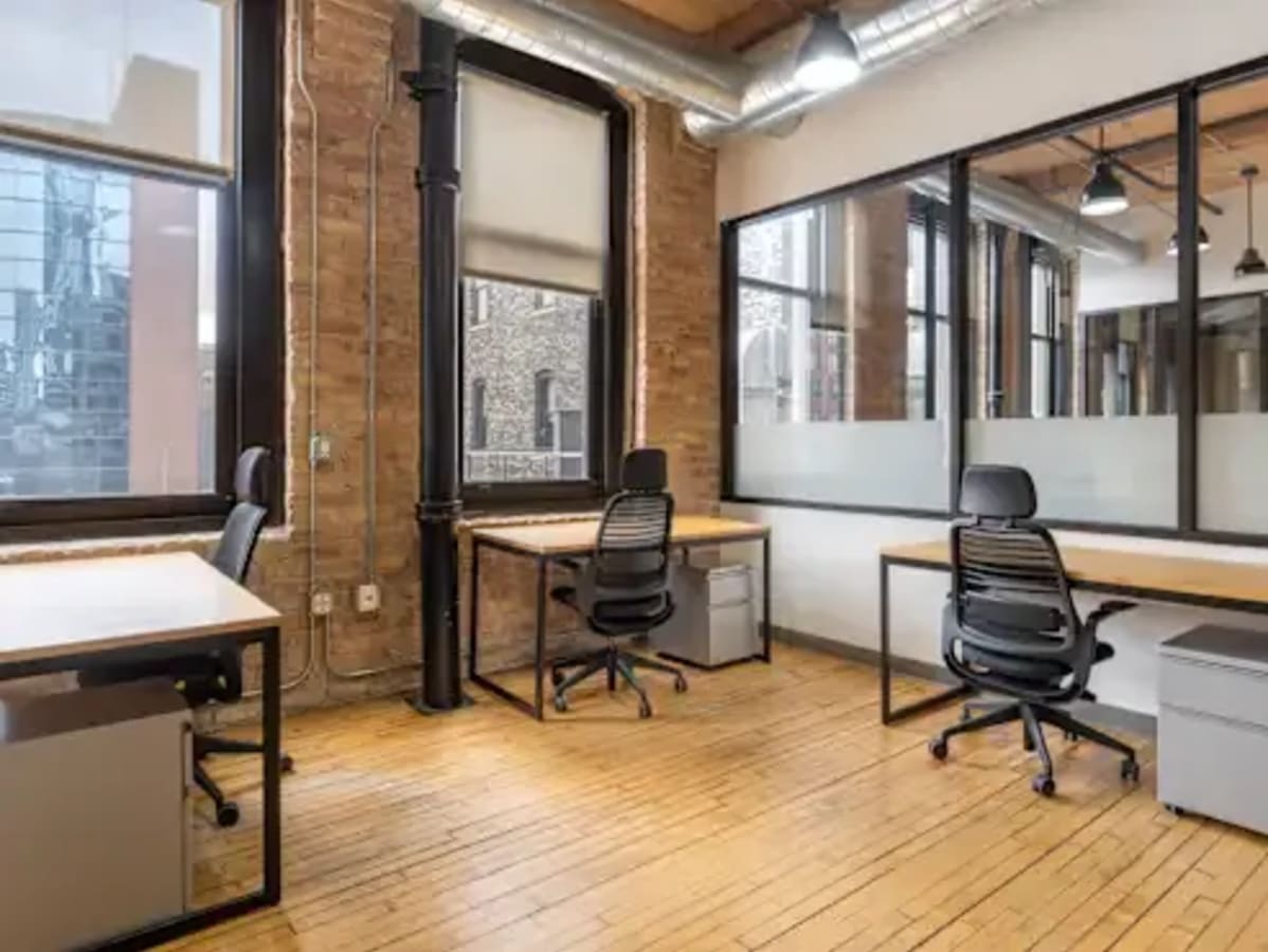 Bright coworking space with exposed brick, large windows, and modern furnishings in Maharashtra.