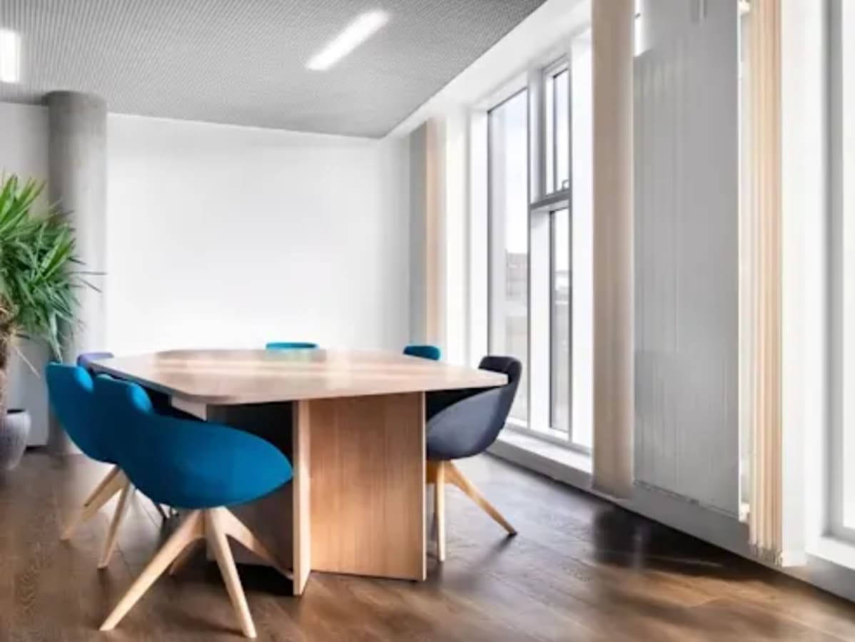 Bright coworking space with modern chairs, wooden table, and abundant natural light.