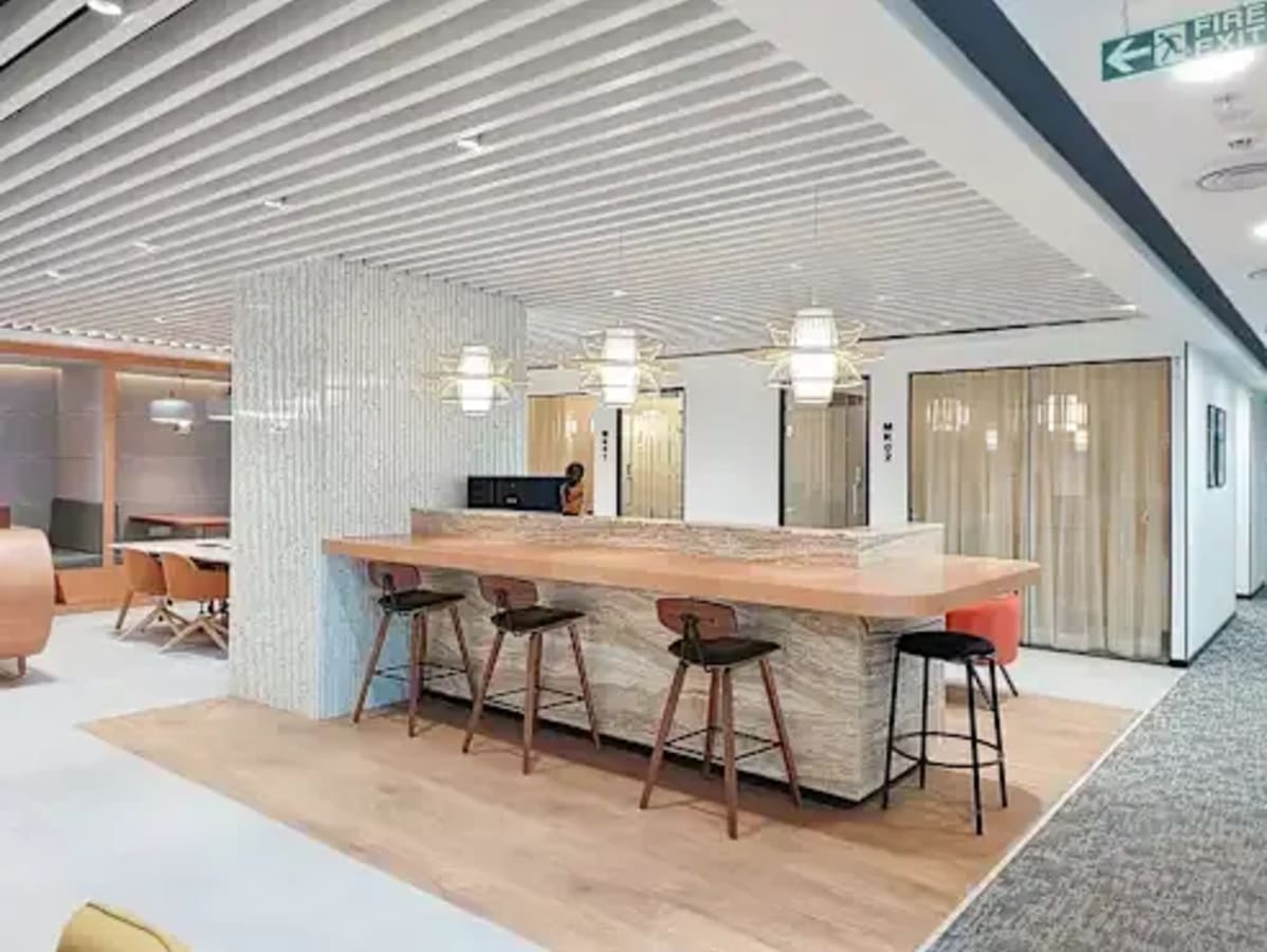 Modern coworking space in Powai featuring a sleek wooden bar and stylish seating.