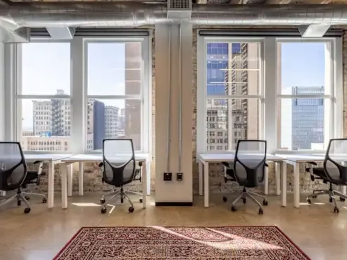 Bright coworking space with modern desks, ergonomic chairs, and stunning city views.