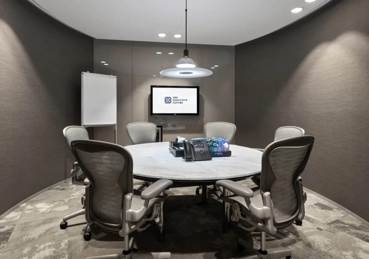 Sleek meeting room with ergonomic chairs, round table, and modern AV setup in Battery Road coworking space.