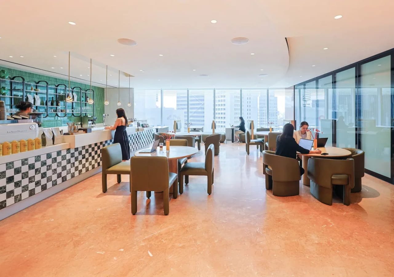 Vibrant coworking space with modern decor, large windows, and a stylish café in Collyer Quay.