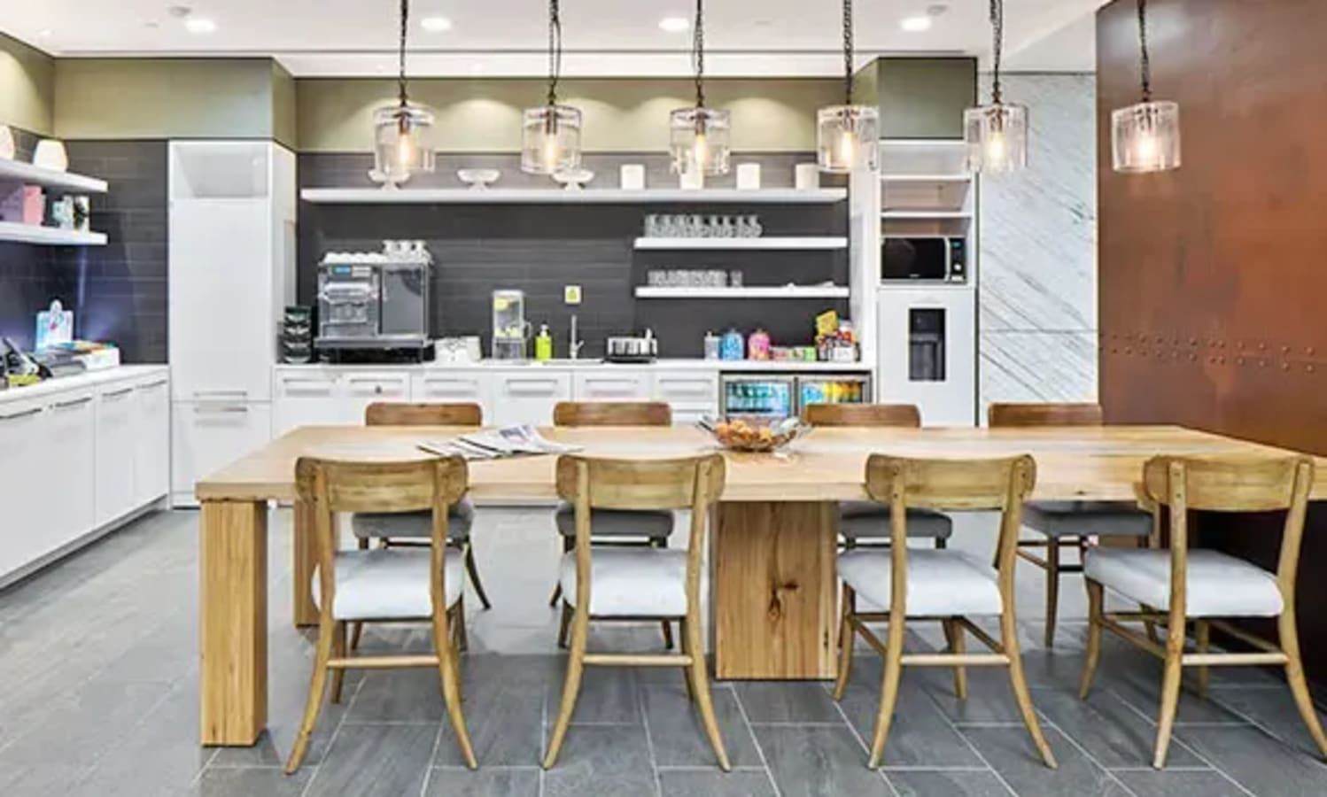 Modern coworking kitchen with ample seating, stylish lighting, and sleek appliances in Gateway West.