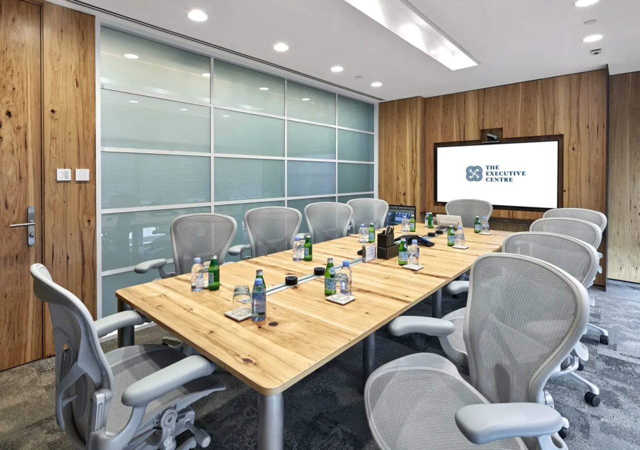 Modern conference room with ergonomic seating, natural wood table, and AV setup in Gateway West.