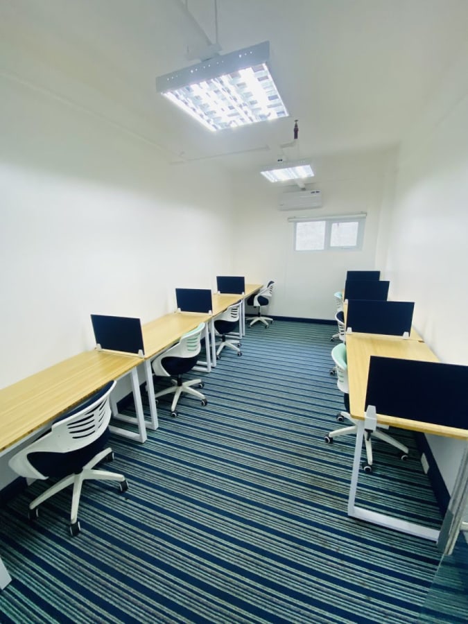 Modern coworking space with natural light, ergonomic chairs, and ample desk space.