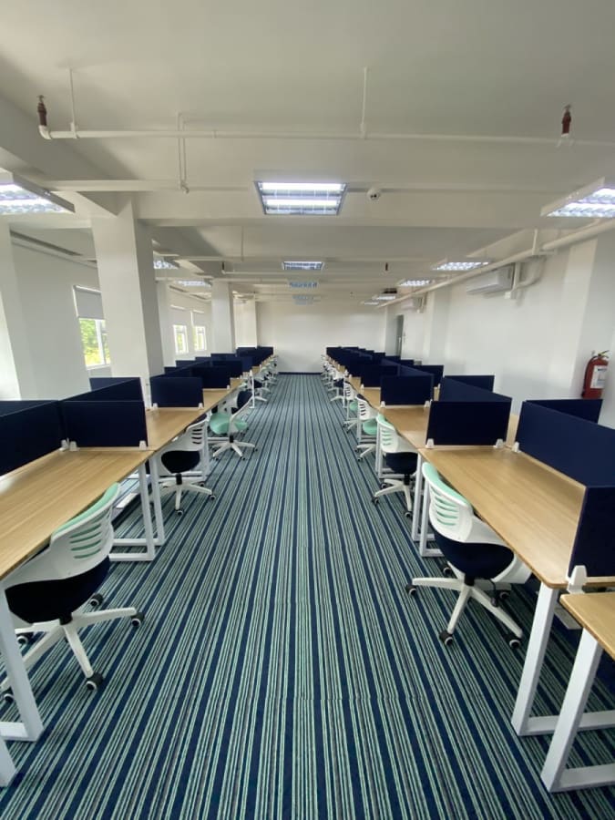 Spacious coworking area with modern desks, ergonomic chairs, and ample natural light.