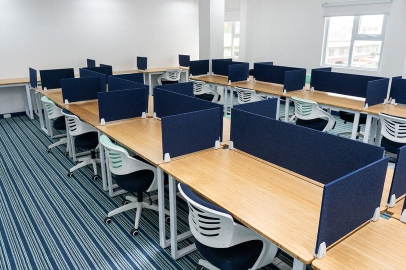 Modern coworking space with ample seating, partitions, and natural light for productivity.