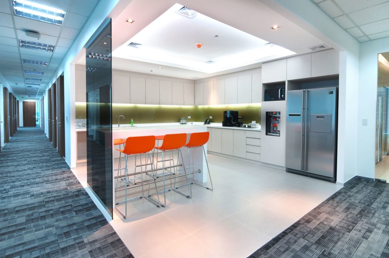 Modern coworking space with sleek kitchen, vibrant seating, and ample natural light.
