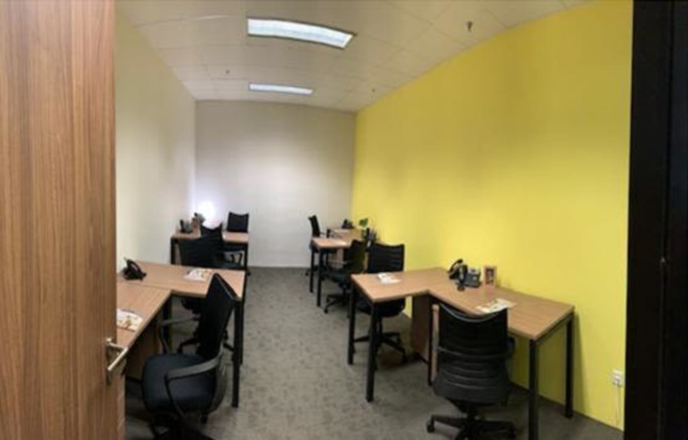 Bright workspace with individual desks, ergonomic chairs, and vibrant yellow accents.