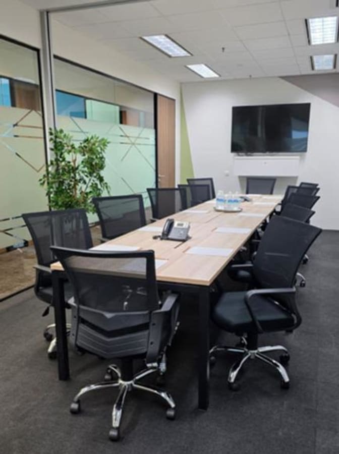 Modern meeting room with sleek chairs, large screen, and natural light in Temasek Boulevard coworking space.