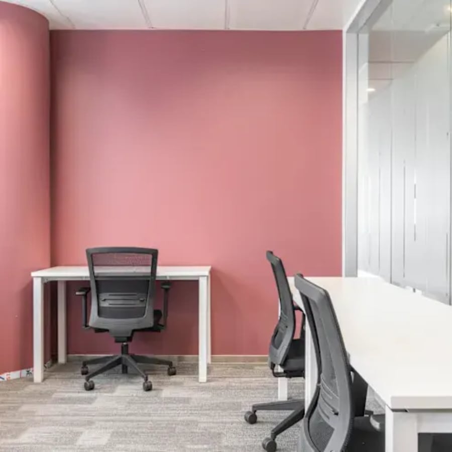 Modern coworking space with sleek desks, ergonomic chairs, and vibrant accent wall. Ideal for productivity.