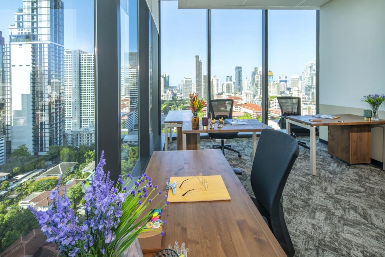 Bright coworking space with city views, modern desks, and comfortable chairs.