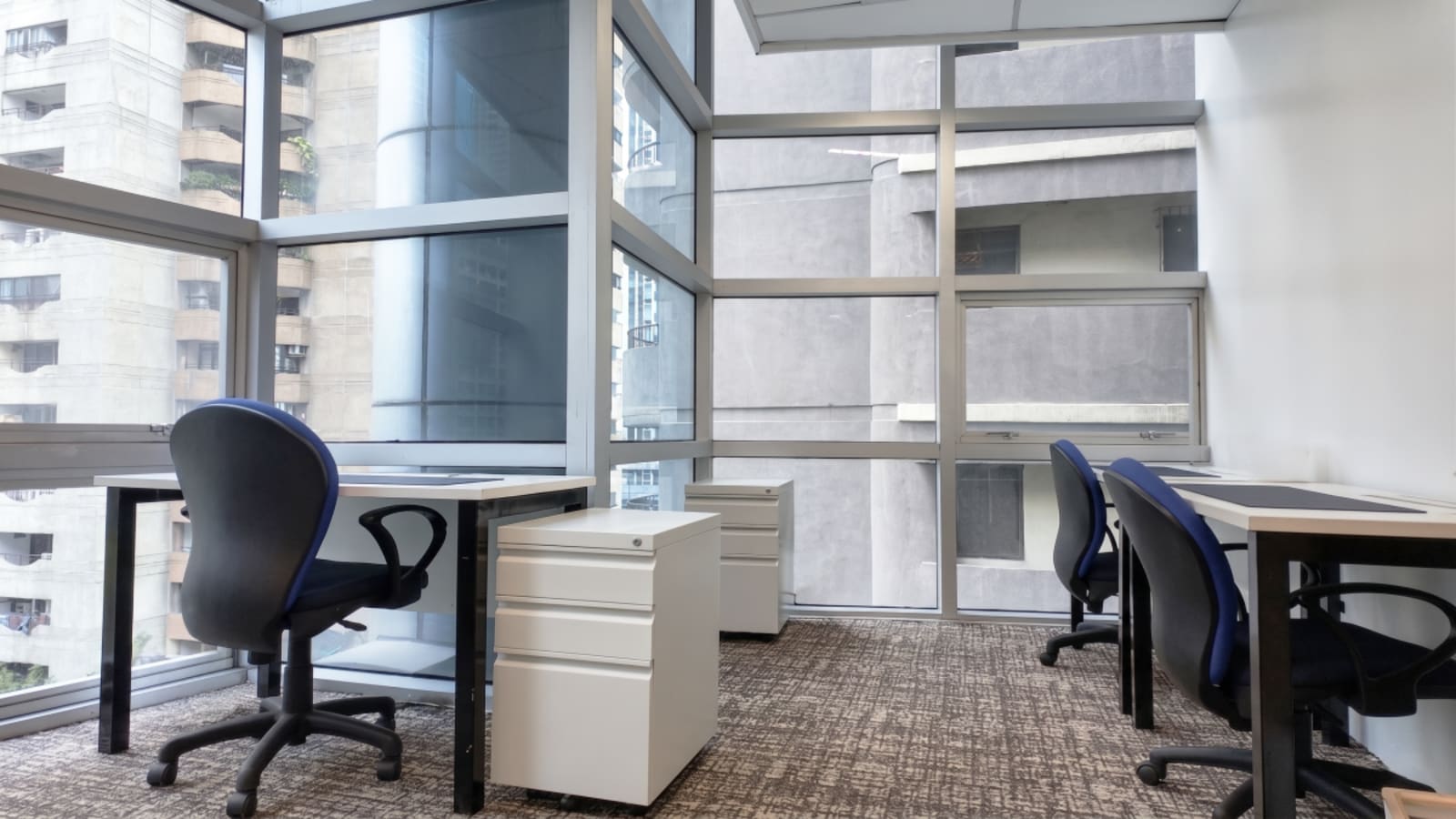 Modern coworking space with floor-to-ceiling windows, comfortable chairs, and ample natural light.