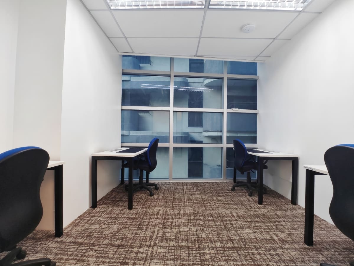 Bright coworking space with modern desks, ergonomic chairs, and natural light from large windows.