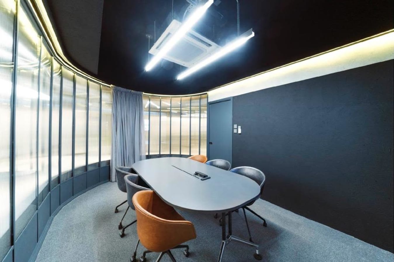 Sleek meeting room with modern lighting, curved glass walls, and stylish seating in Chai Wan Kok.