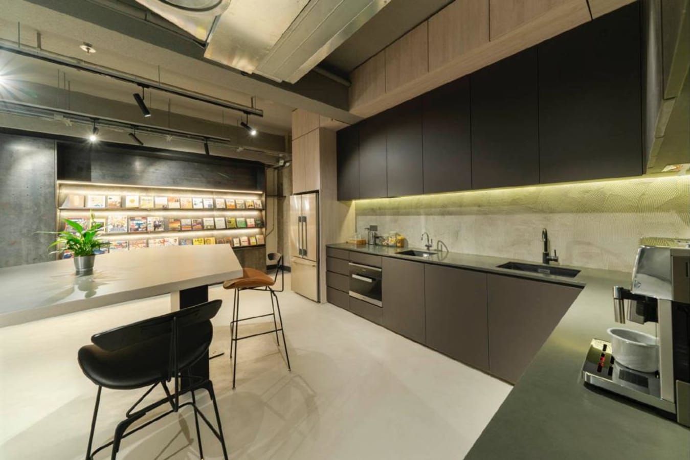 Modern coworking kitchen with sleek cabinetry, bar seating, and ample lighting. Perfect for breaks.