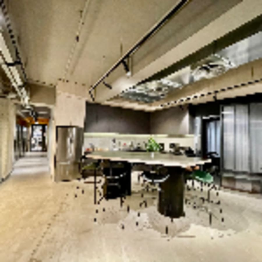 Modern coworking space with open-plan design, high ceilings, and collaborative meeting area.