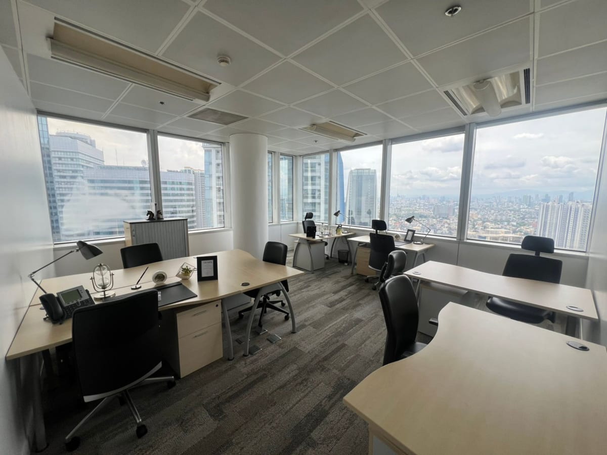 Bright coworking space with panoramic city views, modern desks, and ergonomic chairs.