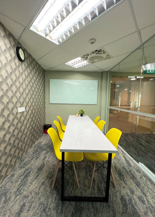 Vibrant meeting room with bright yellow chairs, modern wallpaper, and natural lighting.