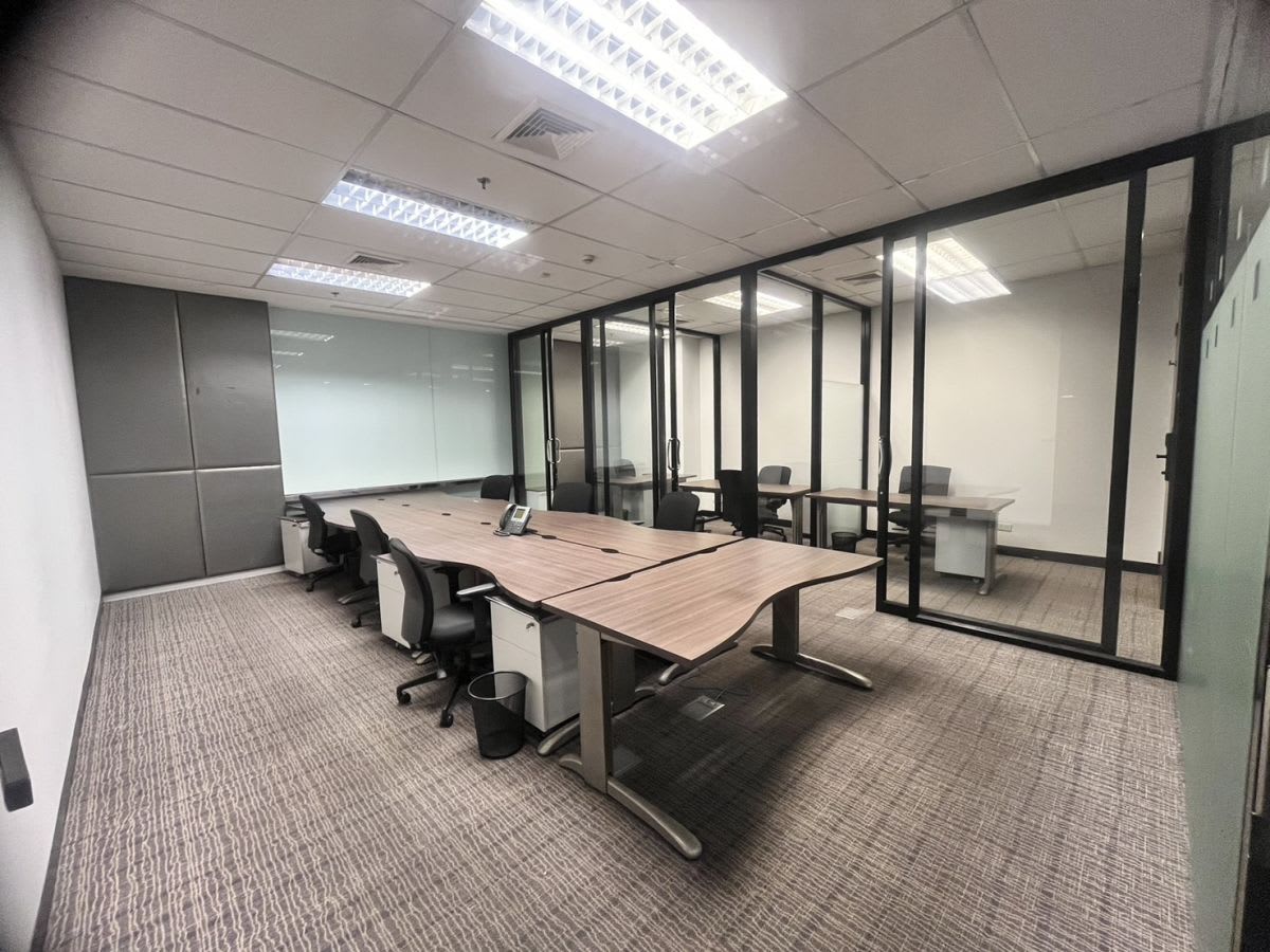 Modern coworking space featuring open desks, glass partitions, and ample natural light.