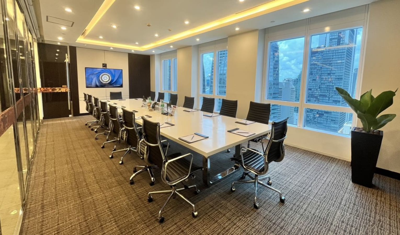 Spacious conference room with city views, sleek chairs, and modern AV setup in a vibrant location.
