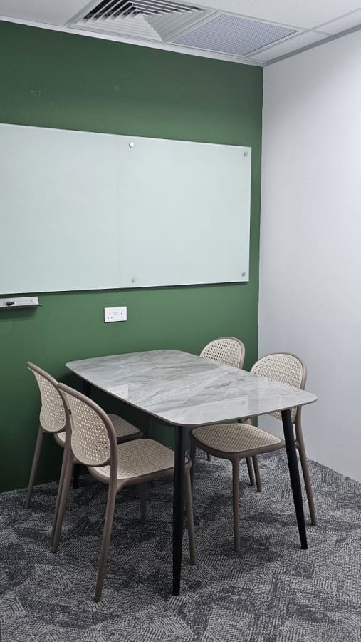 Modern meeting nook with sleek table, seating for four, and whiteboard. Perfect for collaboration.