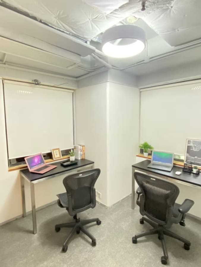 Bright, modern workspace with two desks, ergonomic chairs, and ample natural light. Ideal for productivity.