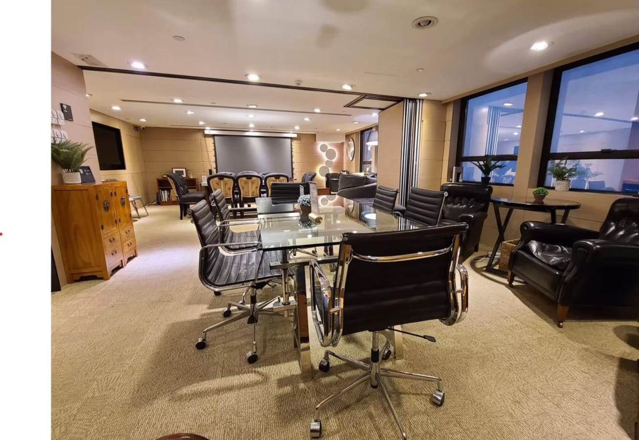 Modern coworking space with sleek glass table, leather chairs, and natural light on Hysan Avenue.