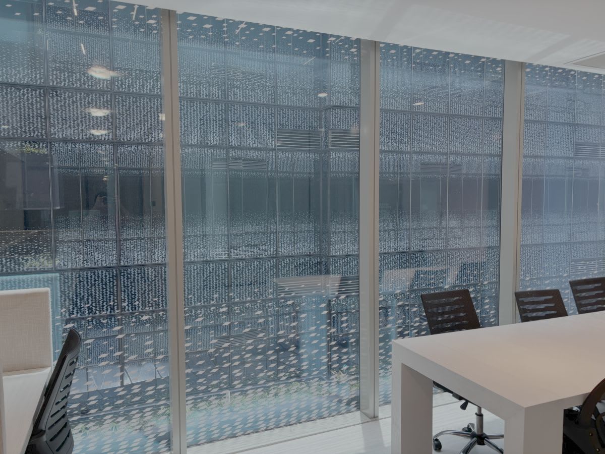 Bright coworking space with modern desks and ergonomic chairs, enhanced by expansive glass walls.