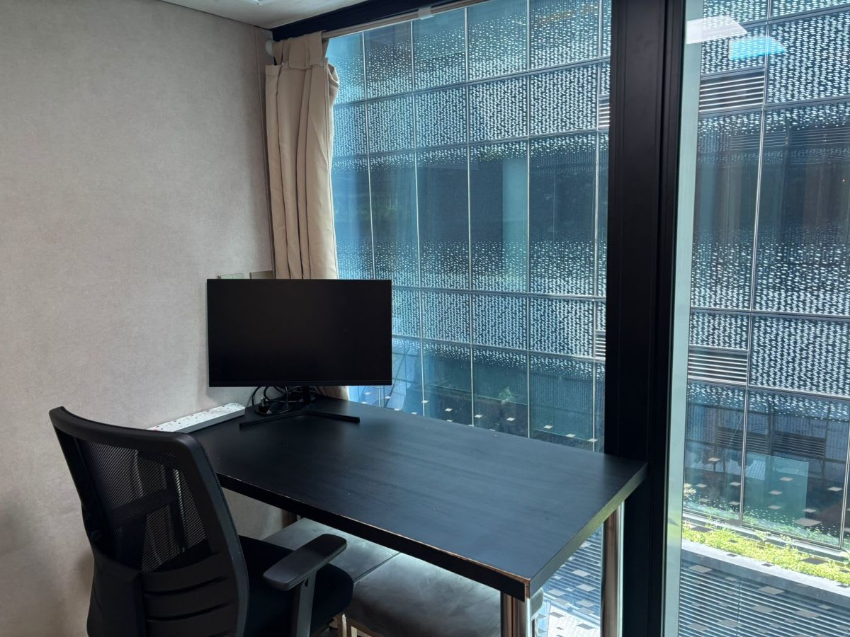 Bright, modern coworking space with large window, ergonomic chair, and sleek desk setup.