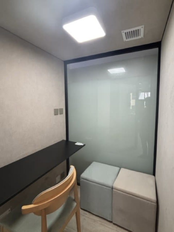 Compact coworking pod with modern seating and soft lighting for focused work.