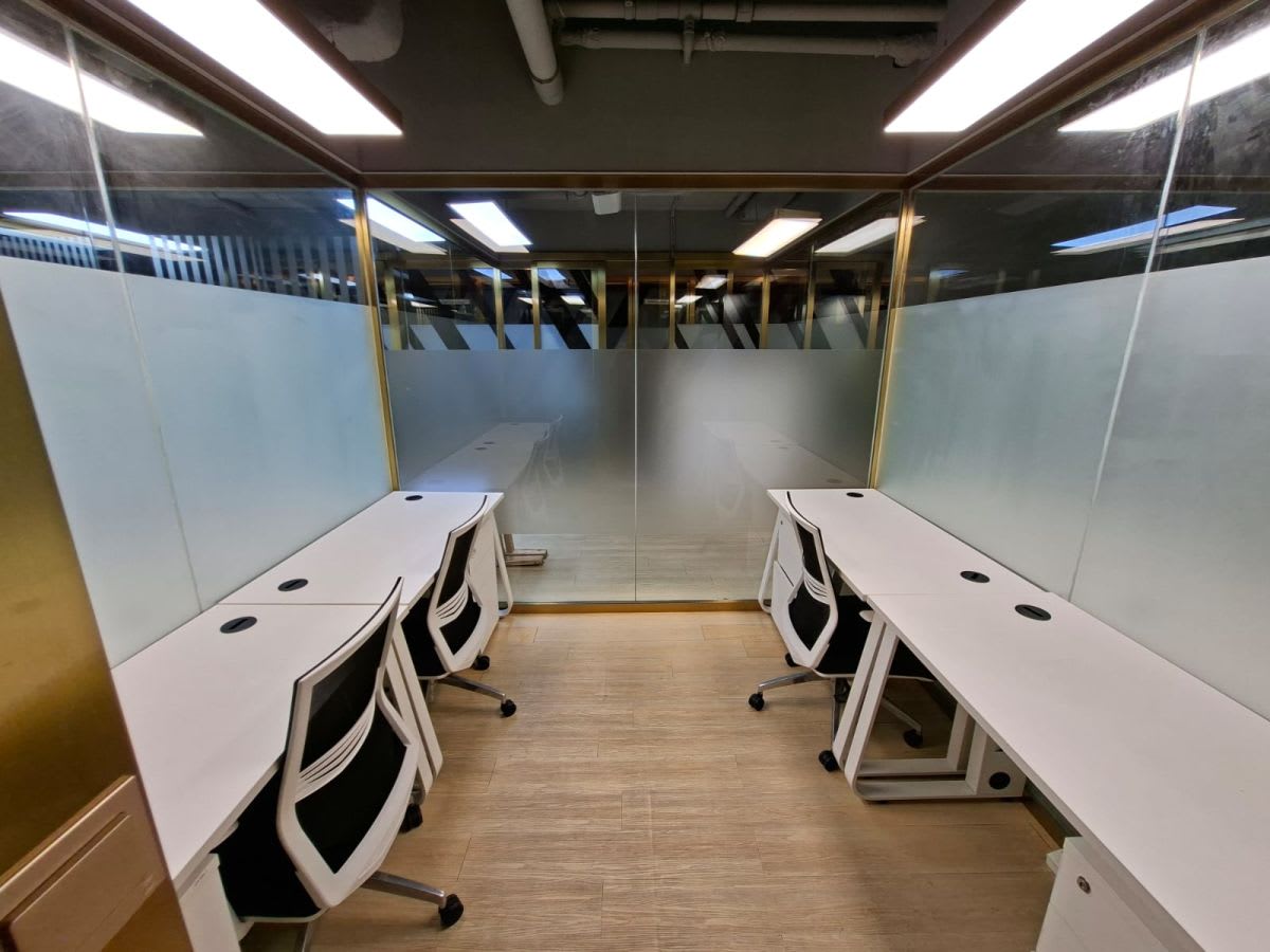 Modern, glass-enclosed workspace with ergonomic chairs and natural lighting, ideal for collaboration.
