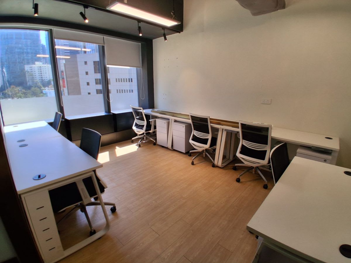 Bright coworking space with modern desks, ergonomic chairs, and large windows for natural light.