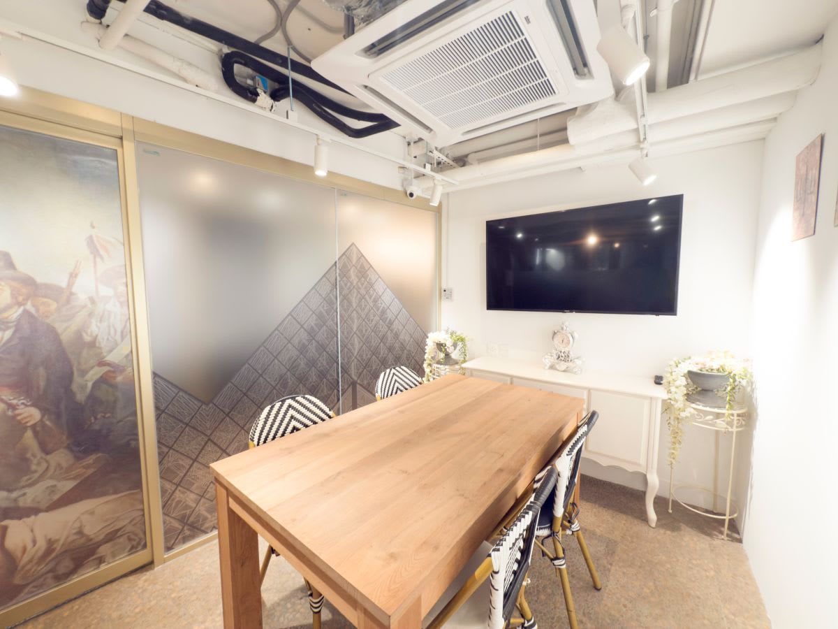 Chic meeting room with modern decor, natural wood table, and smart TV in prime Central location.