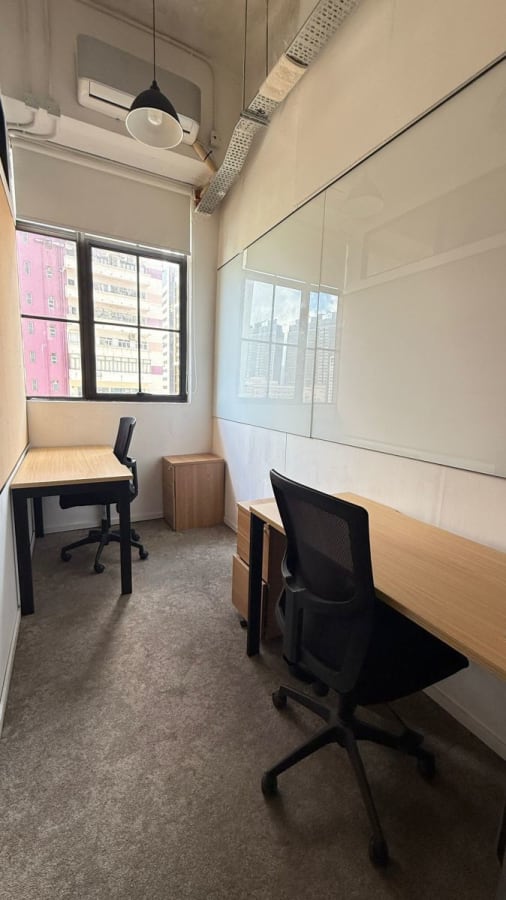 Bright coworking space with modern desks, ergonomic chairs, large windows, and sleek whiteboard.