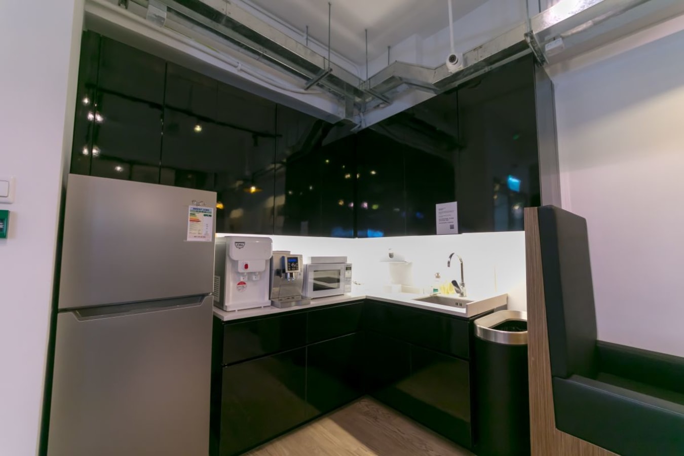 Modern pantry area with sleek black cabinetry and essential appliances for a productive workspace.