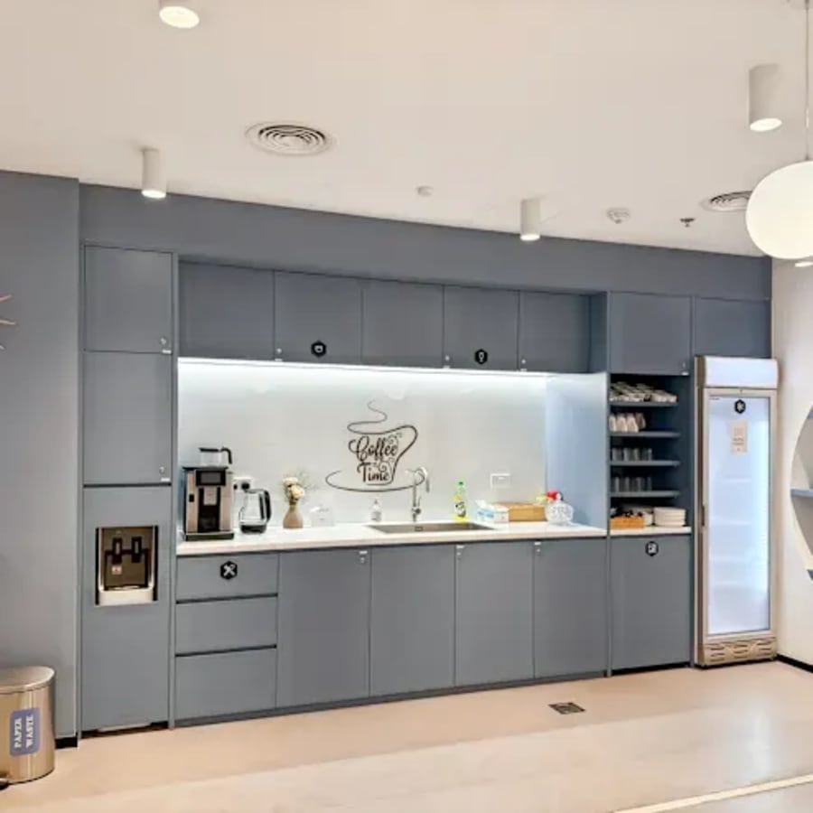 Modern kitchenette with coffee station and ample storage, ideal for a dynamic coworking atmosphere.