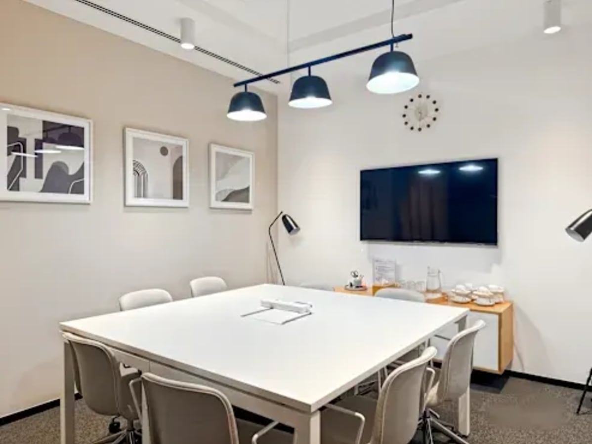 Modern meeting room with ample seating, sleek lighting, and a large screen. Perfect for collaboration.