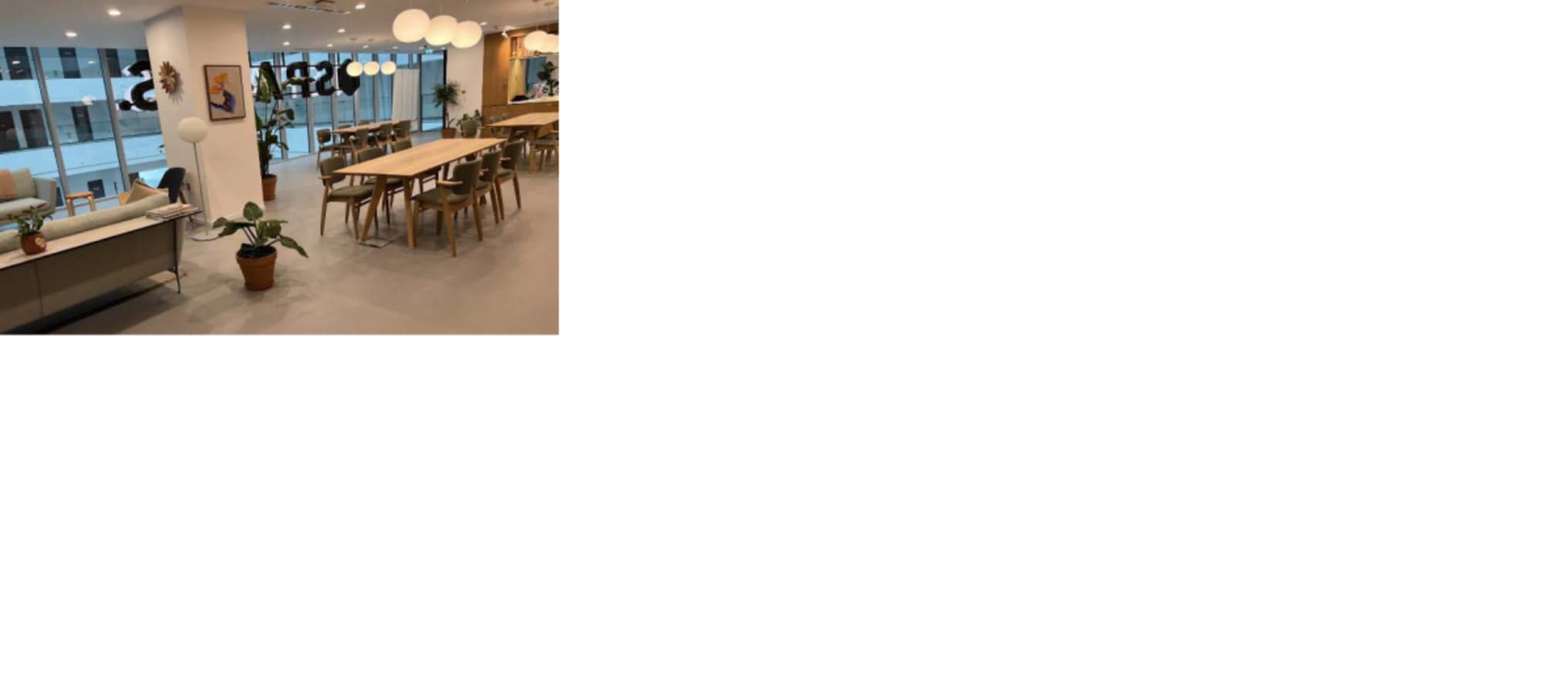 Modern coworking space with natural lighting, communal tables, and comfortable seating. Perfect for collaboration.